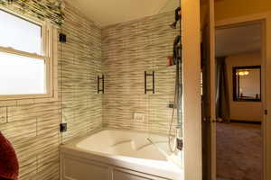 Bathroom featuring tile walls and plus tub/shower