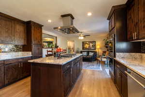 Kitchen featuring appliances with stainless steel finishes, ceiling fan, backsplash, and light hardwood / wood-style flooring