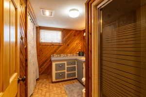 Bathroom featuring toilet, wooden walls, a shower with door, and a textured ceiling. washer/dryer hookups