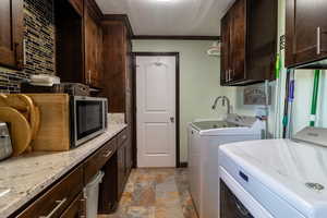 Laundry room with separate washer and dryer, ornamental molding, and cabinets