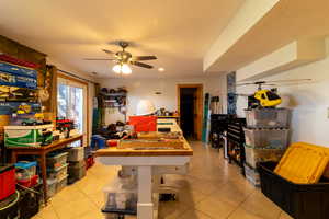 Basement family room with  light tile patterned floors, ceiling fan and walk-out door to backyard