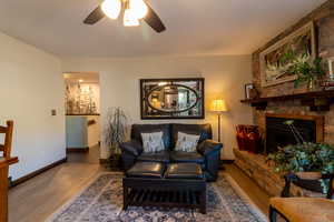 Family room featuring ceiling fan, hardwood / wood-style flooring, and a fireplace. Adjacent to kitchen