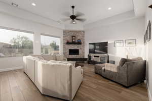 Living room featuring ceiling fan, hardwood / wood-style flooring, and a fireplace