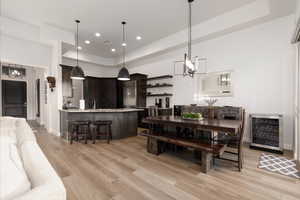 Dining space featuring light hardwood / wood-style flooring, wine cooler, sink, and a chandelier