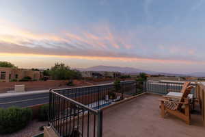 Patio terrace at dusk featuring a mountain view and a balcony