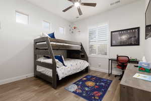 Bedroom with ceiling fan, hardwood / wood-style floors, and multiple windows