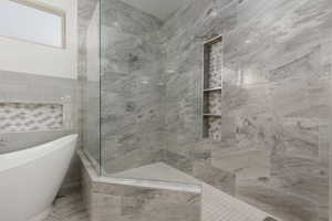 Bathroom featuring tile walls and shower with separate bathtub