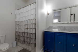 Bathroom with tile patterned floors, walk in shower, toilet, ceiling fan, and vanity