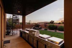 Patio terrace at dusk featuring an outdoor kitchen, sink, and a grill