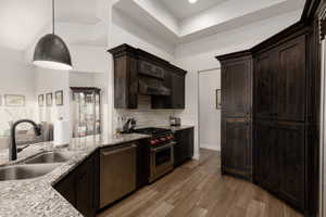 Kitchen featuring backsplash, light wood-type flooring, stainless steel appliances, sink, and pendant lighting