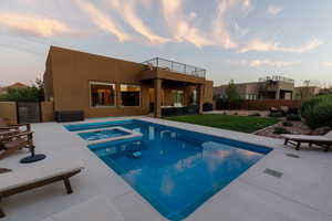 Pool at dusk with a patio area and an in ground hot tub