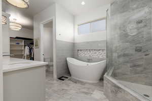 Full bathroom featuring shower with separate bathtub, toilet, vanity, and tile walls