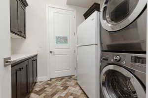 Laundry area featuring stacked washer and clothes dryer and cabinets