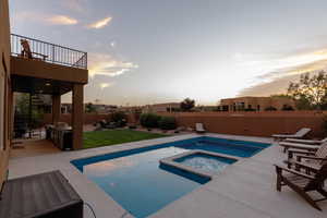 Pool at dusk with a patio and an in ground hot tub