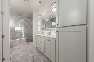 Bathroom featuring vanity, lofted ceiling, and a tile shower