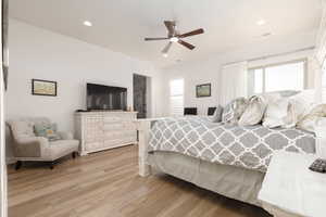 Bedroom featuring ceiling fan, multiple windows, and light hardwood / wood-style floors