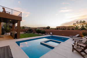 Pool at dusk with a patio area and an in ground hot tub