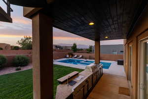 Pool at dusk featuring a yard and a patio