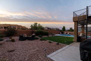 Yard at dusk with a fenced in pool and a patio area