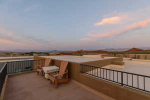 Patio terrace at dusk featuring a balcony and a mountain view