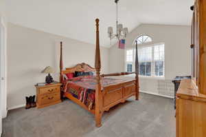 Carpeted bedroom with lofted ceiling and a chandelier