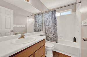 Full bathroom with shower / bathtub combination with curtain, wood-type flooring, toilet, and vanity