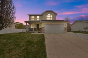 View of front of property with a garage, a porch, and a lawn