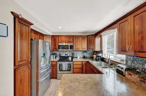 Kitchen with light hardwood / wood-style flooring, backsplash, stainless steel appliances, and sink