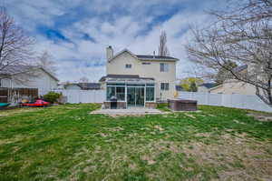 Rear view of property with a lawn, a patio, and a sunroom