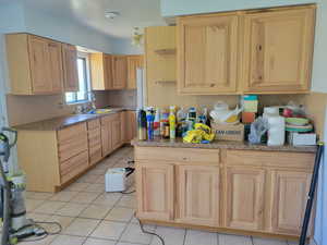 Kitchen featuring light brown cabinetry, sink, and light tile patterned floors