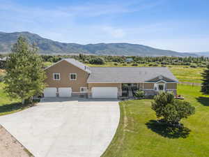 Single story home with a mountain view, a front yard, and a garage