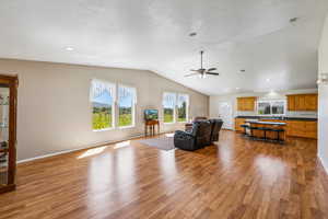 Living room with light wood-type flooring, ceiling fan, and vaulted ceiling