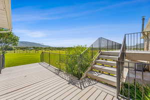 Wooden terrace featuring a mountain view and a lawn