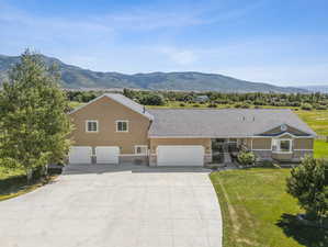 View of front of home featuring a mountain view, a garage, and a front lawn