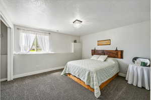 Bedroom featuring dark carpet and a textured ceiling