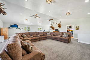 Living room featuring carpet, ceiling fan, and vaulted ceiling