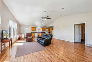 Living room with lofted ceiling, light hardwood / wood-style flooring, and ceiling fan