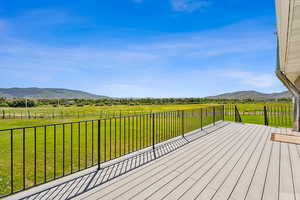 Deck with a lawn, a rural view, and a mountain view