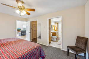 Carpeted bedroom with ceiling fan, connected bathroom, and sink