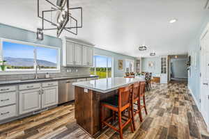 Kitchen featuring a mountain view, dishwasher, a kitchen island, sink, and dark wood-type flooring