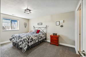 Bedroom with a textured ceiling and dark carpet