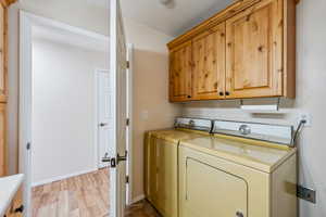 Laundry area featuring washer and dryer, cabinets, and light hardwood / wood-style floors