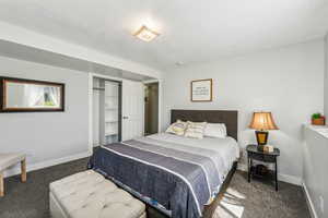 Bedroom with dark colored carpet and a closet