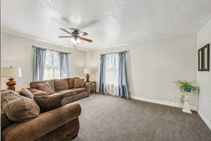 Carpeted living room featuring a textured ceiling and ceiling fan