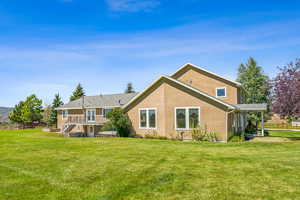 Rear view of house featuring a yard and a deck