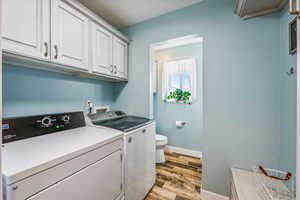 Clothes washing area featuring washer and dryer and light hardwood / wood-style floors