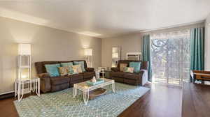 Living room with a wealth of natural light, wood-type flooring, and a wall mounted air conditioner