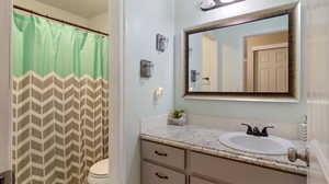 Bathroom with a shower with shower curtain, toilet, and vanity