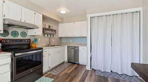 Kitchen featuring appliances with stainless steel finishes, dark hardwood / wood-style floors, white cabinetry, and sink