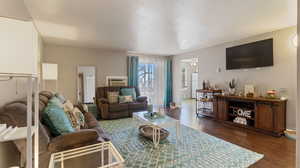 Living room with a textured ceiling, dark hardwood / wood-style floors, and an AC wall unit